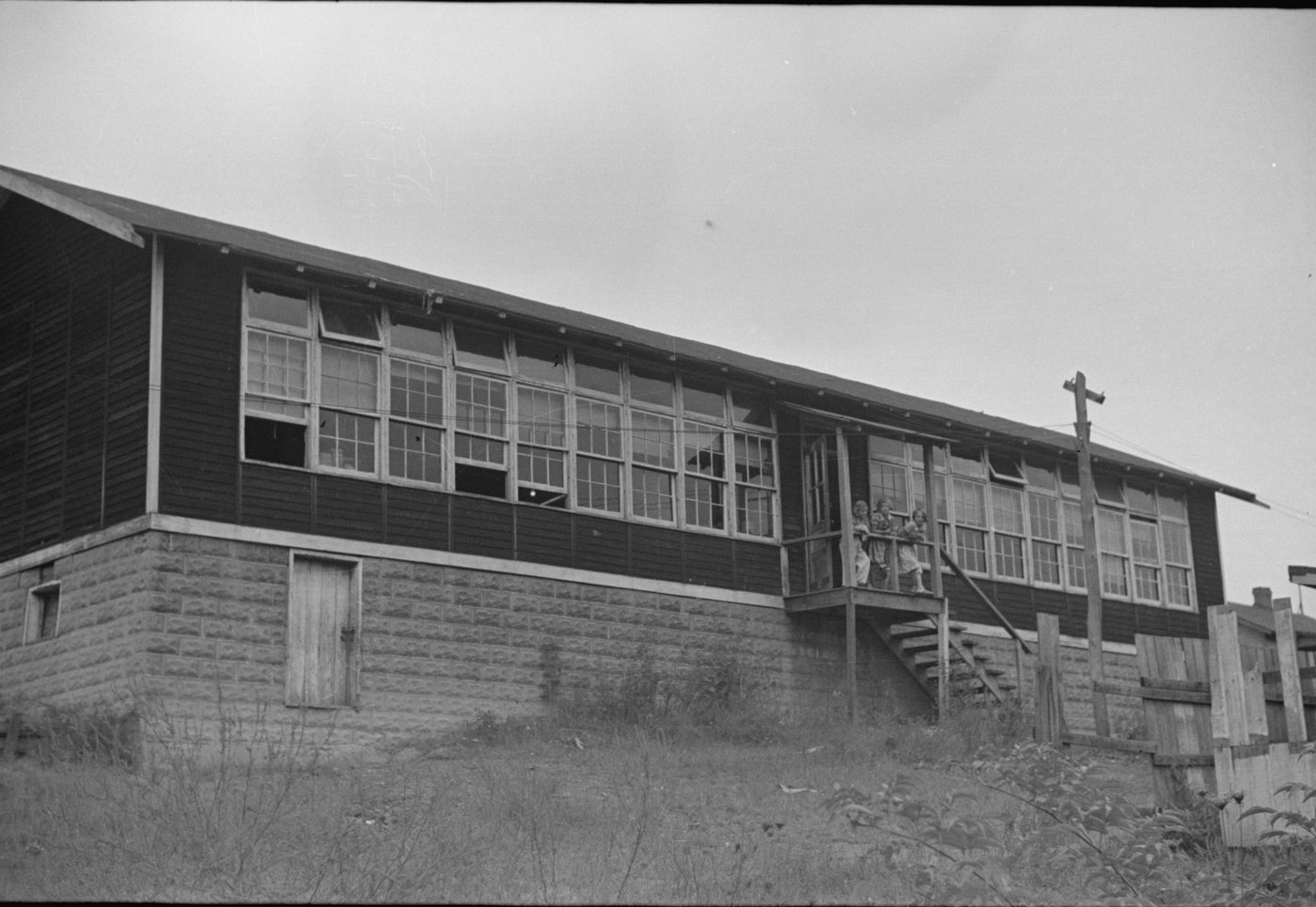 A long school building with rows of windows on a stone foundation