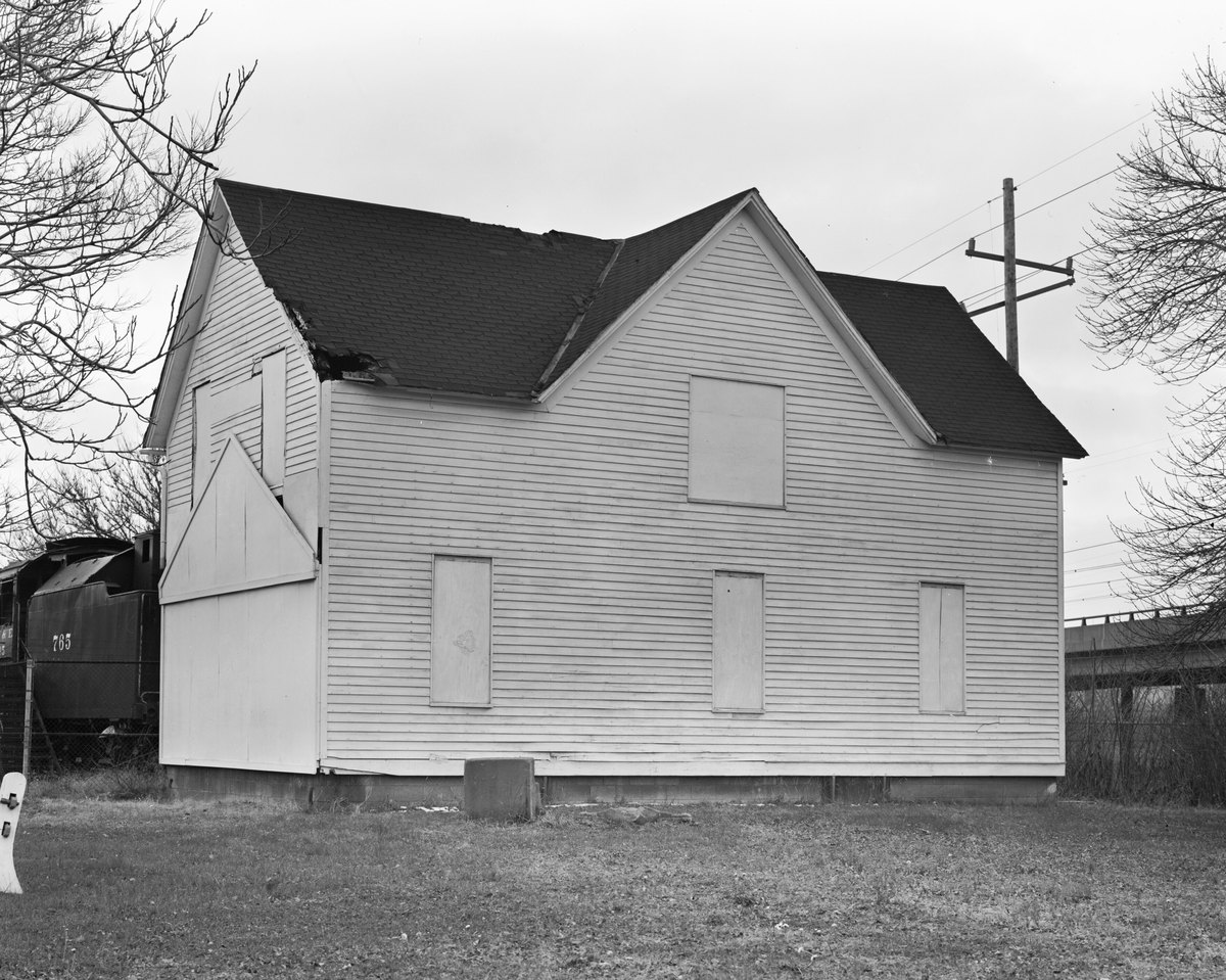 The Gary Land Company Building, a two-storey clapboard house with boarded windows, photographed for the Historic American Buildings Survey