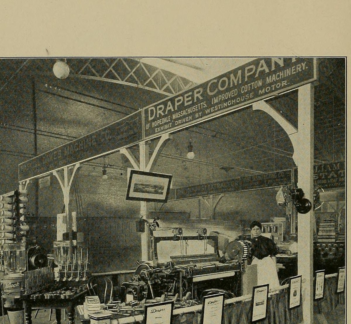 A trade-show stand under a banner reading Draper Company, with looms, bobbins and a woman at a loom