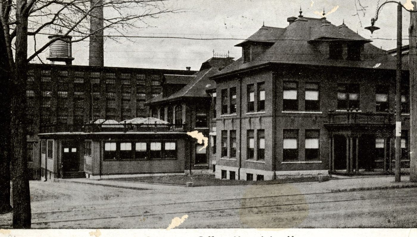 A postcard of the Draper Company's brick office building with a hipped roof, beside the mill and a water tower