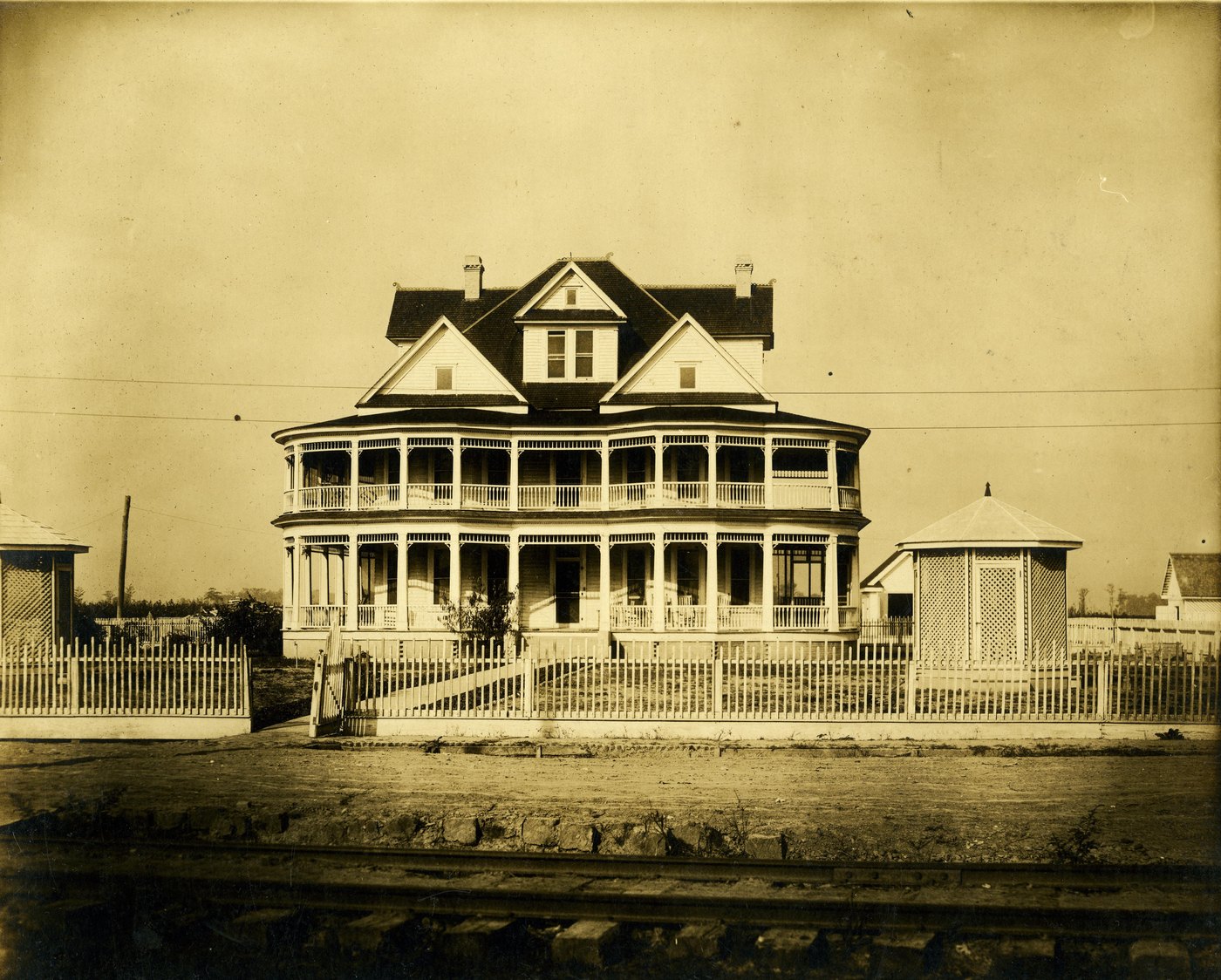 The superintendent's three-storey house at Parchman, with verandas, a picket fence and a railway line in front